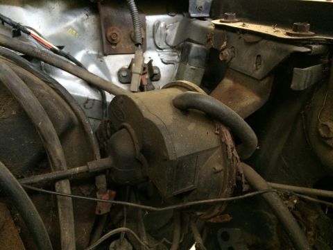 1986 Ford Bronco - This image shows a close-up view of various engine bay components, including hoses and wiring, covered in dust.