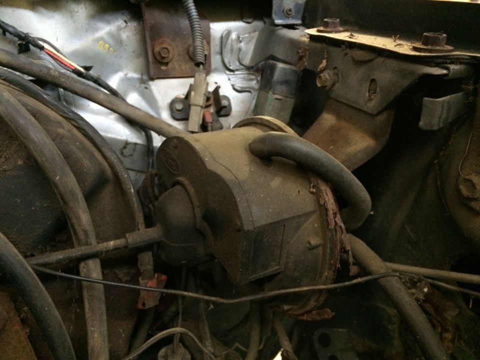 Close-up of dusty engine bay parts with hoses and wires