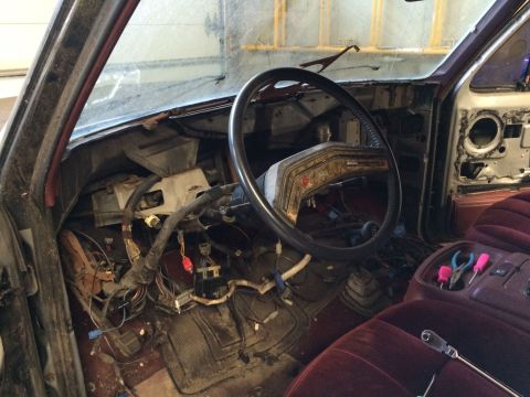 1986 Ford Bronco - Interior view of a 1986 Ford Bronco during disassembly, with exposed wiring and tools on the console.