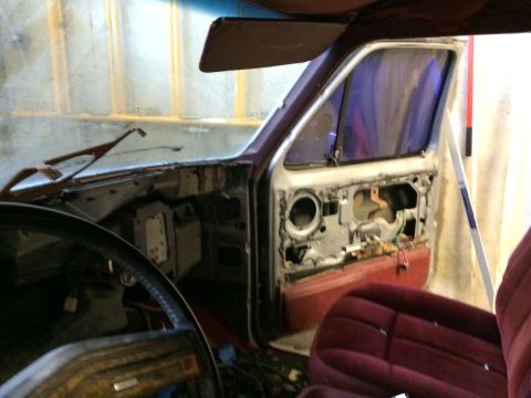 1986 Ford Bronco - The interior of a vehicle is shown with the driver's side door panel removed, revealing its internal components.