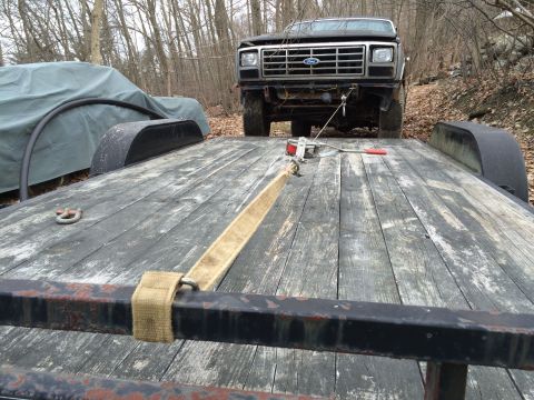 1986 Ford Bronco - A Ford truck is winched onto a wooden trailer, ready for transport.