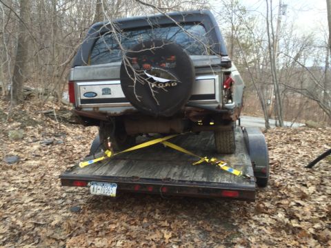 1986 Ford Bronco - A gray Ford Bronco is loaded onto a trailer for transport.
