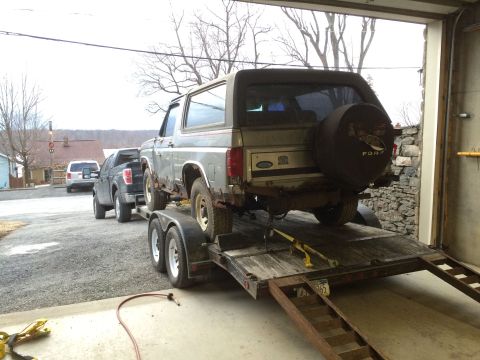 1986 Ford Bronco - A Ford Bronco and a pickup truck are being transported on a trailer.