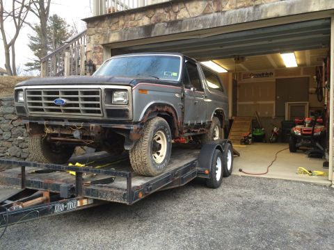 1986 Ford Bronco - This Ford Bronco is being transported on a trailer, showing signs of wear and tear.