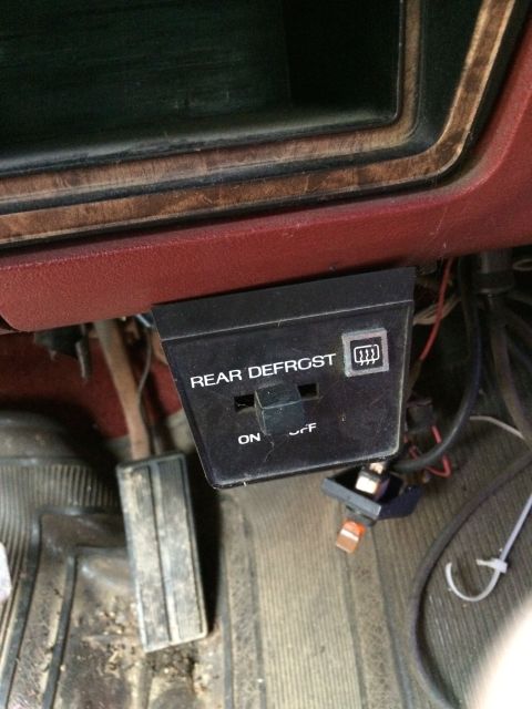 1986 Ford Bronco - A close-up of the interior reveals a rear defrost switch and the vehicle's pedals.