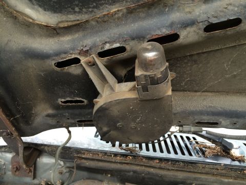 1986 Ford Bronco - Close-up of an under-hood component, likely a motor or actuator, showing signs of rust and wear.