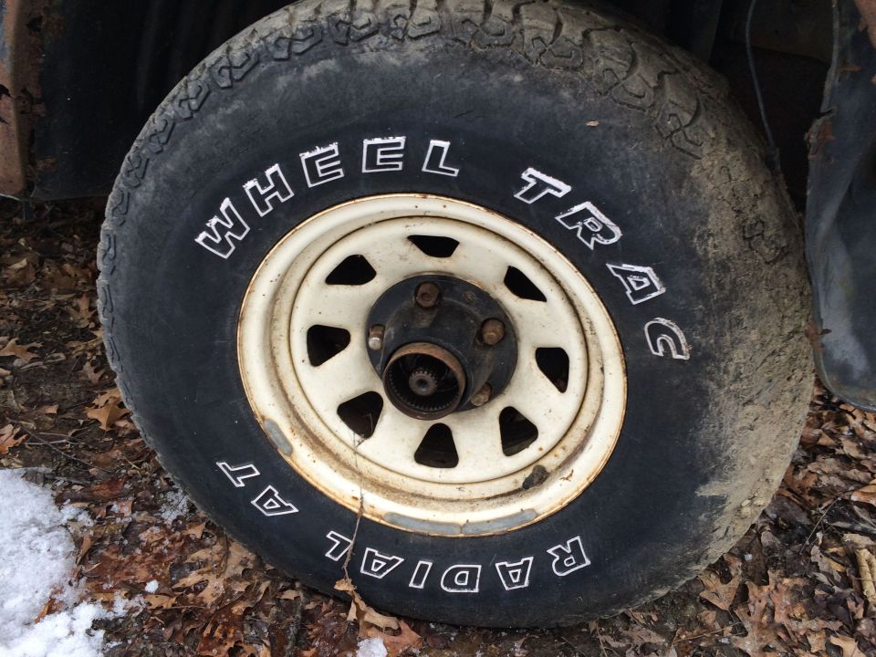 Close-up of a tire with 'WHEEL TRAC' and 'RADIAL AT' written on it, mounted on a white rim
