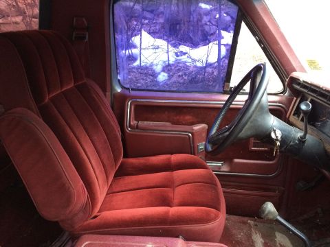 1986 Ford Bronco - Interior view of a 1986 Ford Bronco, plush red velour seats and the dashboard.