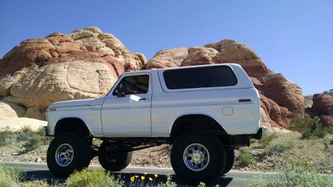 1979 Ford Bronco - This lifted 1979 Ford Bronco is captured in a three-quarter front view against a backdrop of striking red rock formations.