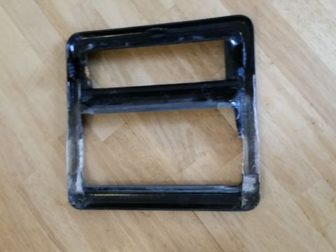1988 Ford Bronco - This is a close-up of a black plastic trim piece, likely for a vehicle's interior or exterior, resting on a wooden surface.