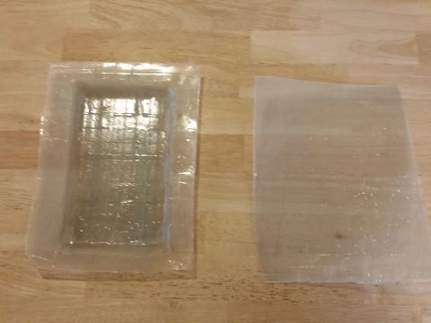 1988 Ford Bronco - Two pieces of clear plastic, one molded and one flat, rest on a wooden surface.