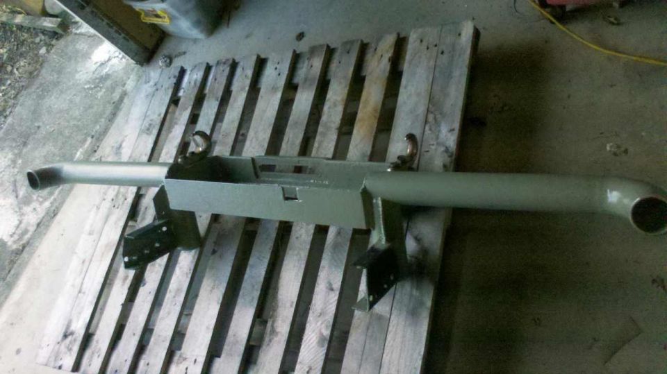 Painted bumper assembly with tow hooks and mounting brackets, resting on wooden pallets