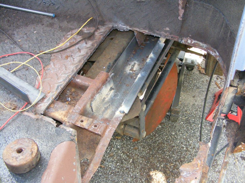 Rusted floor pan and frame with exposed metal and wiring