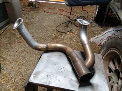 1978 Ford Bronco - Custom exhaust pipes sit on a metal table in a workshop.
