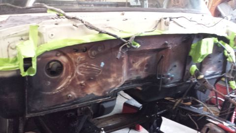 1978 Ford Bronco - The firewall of a vehicle shows significant rust and is partially covered with green masking tape.