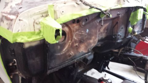 1978 Ford Bronco - The firewall of a vehicle is shown, partially covered in green masking tape, indicating preparation for work.