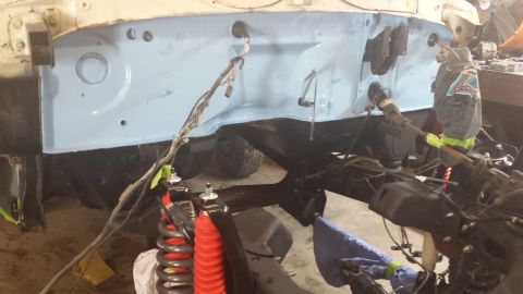 1978 Ford Bronco - Firewall and frame of a vehicle being worked on, showing suspension parts and wiring.