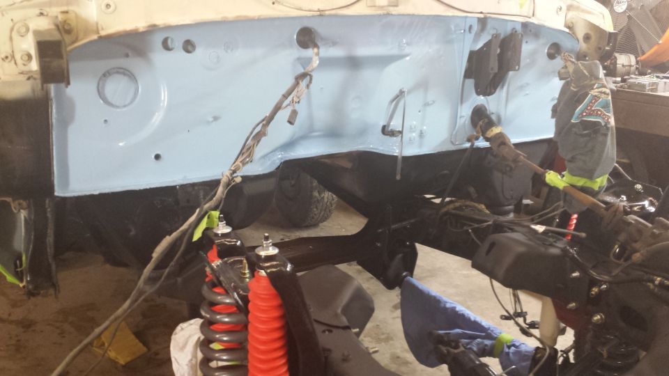 Vehicle firewall and frame with suspension components visible, undergoing restoration