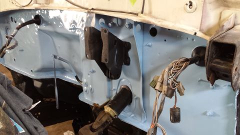 1978 Ford Bronco - The firewall of a vehicle is shown, painted light blue, with various wires and brackets attached.