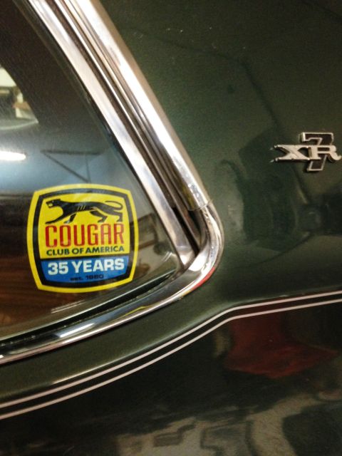 1968 Mercury Cougar - A sticker celebrates 35 years of the Cougar Club of America, alongside an XR7 emblem on a dark green vehicle.