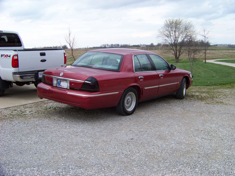 Red sedan parked on gravel next to a white pickup truck