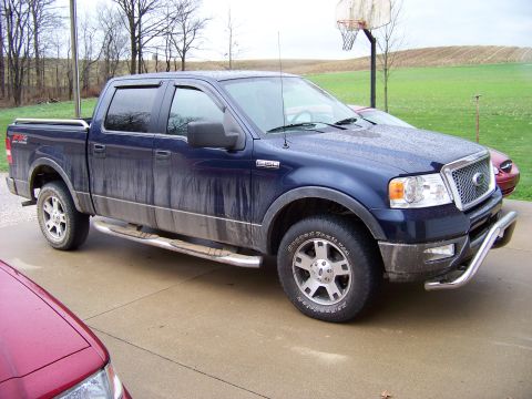 1999 Mercury Grand Marquis - A blue pickup truck is parked on a driveway, showing its front quarter view with a chrome bull bar and running boards.