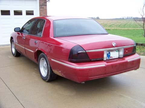 1999 Mercury Grand Marquis - Rear view of a red 1999 Mercury Grand Marquis parked in front of a garage.