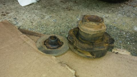 1991 Buick Reatta - Two heavily rusted suspension components are laid out on cardboard, with a concrete surface in the background.