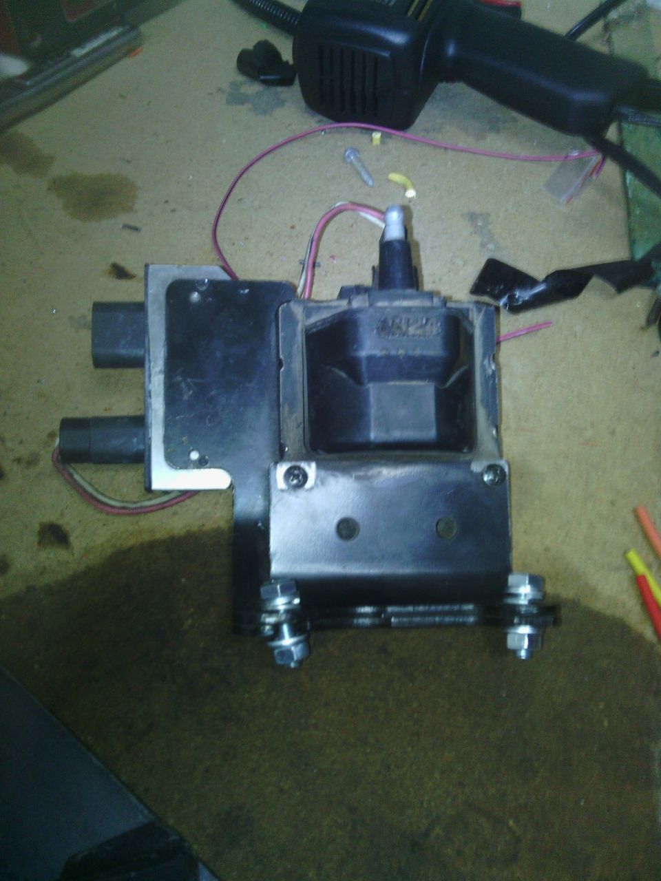 Ignition coil assembly with wires and mounting hardware on a workbench