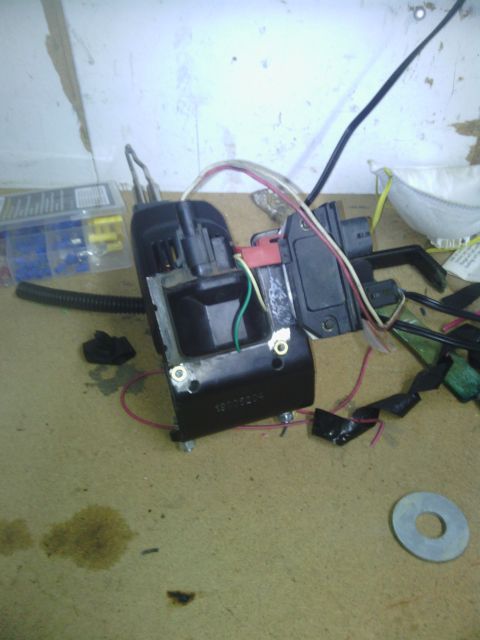 1978 Ford Bronco - A disassembled automotive ignition coil and associated wiring are laid out on a workbench, possibly for repair or replacement.