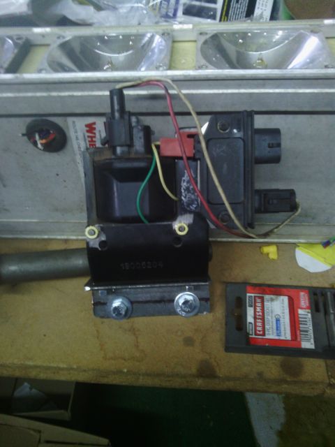 1978 Ford Bronco - An ignition coil assembly with wiring is shown, next to a package of tools.