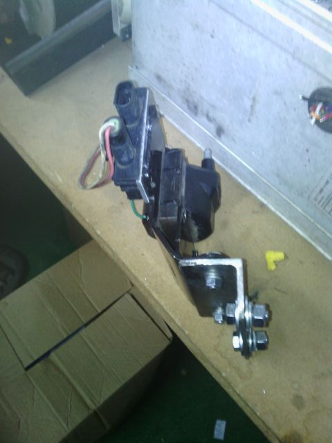 1978 Ford Bronco - Close-up of an automotive ignition coil assembly, likely a replacement part, on a workbench.