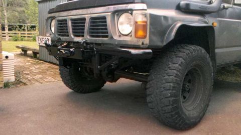 1989 Nissan Patrol - The front of a dark-colored Nissan Patrol is shown, a prominent bull bar and off-road tires.