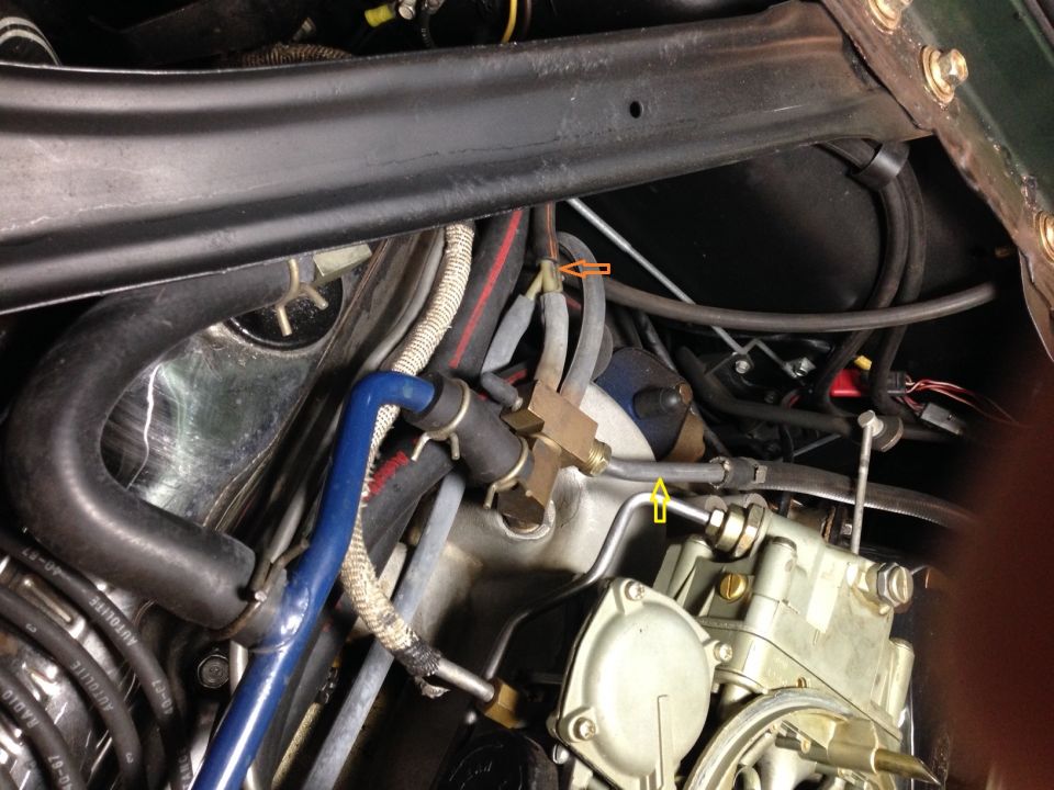 Engine bay with carburetor, blue hose, and metal lines. Yellow and orange arrows point to connections