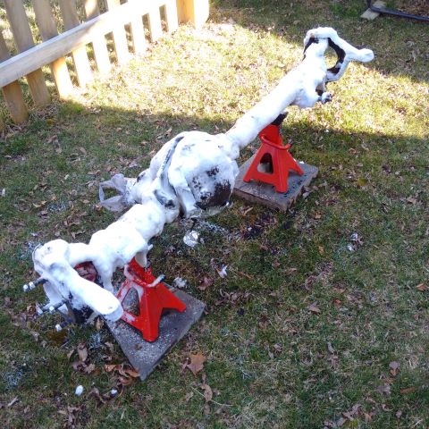 1978 Ford Bronco - A vehicle's front axle, partially covered in snow, is supported by jack stands on a grassy lawn.