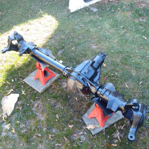 1978 Ford Bronco - A black front axle assembly is supported by red jack stands on a grassy area.