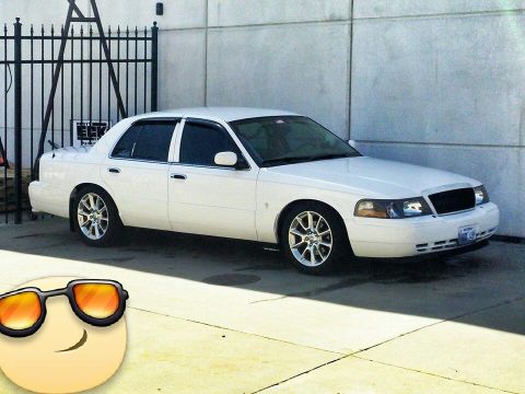 2000 Mercury Grand Marquis - White 2000 Mercury Grand Marquis sedan parked in front of a concrete wall.