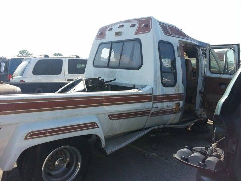 1995 Ford Bronco - Side view of a custom camper truck, showing its open door and some damage. Another vehicle is visible in the background.