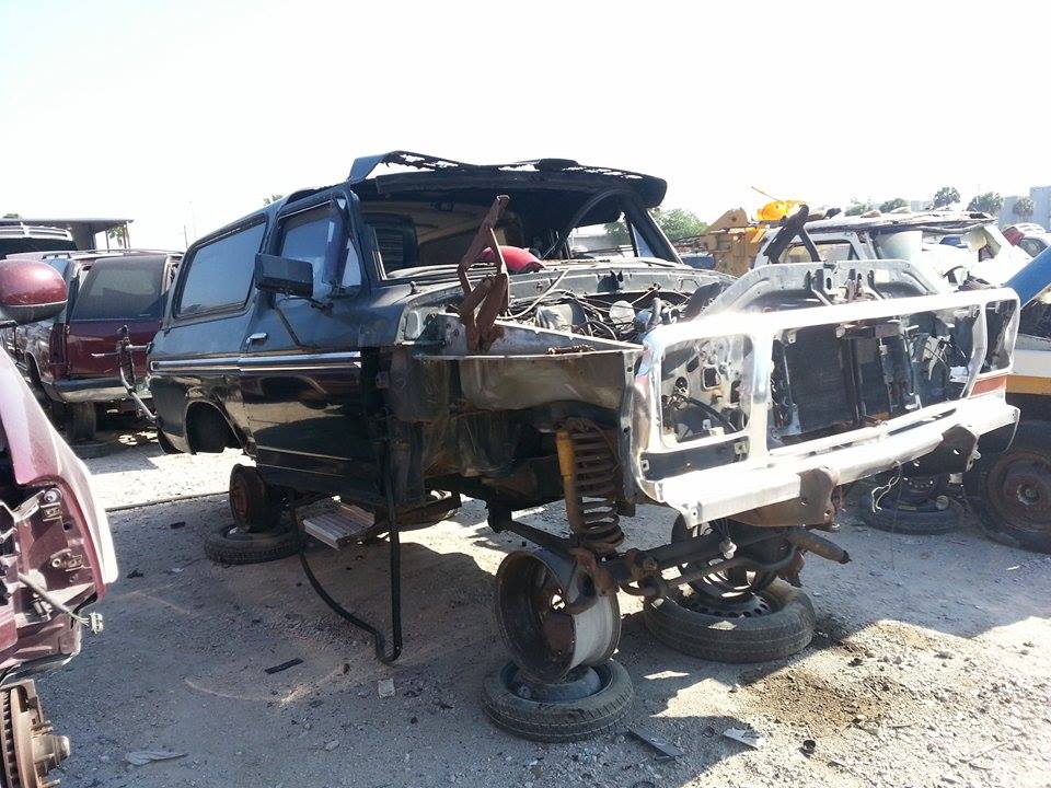 Junkyard Ford Bronco, front view, missing hood and grille, body damaged, wheels removed