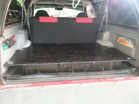 1995 Ford Bronco - Custom platform installed in the cargo area of a red SUV, with storage compartments visible.