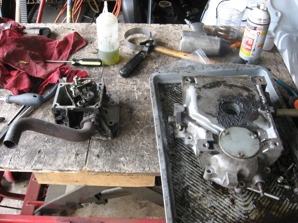 Engine cylinder head and crankcase on a workbench with tools and a red rag