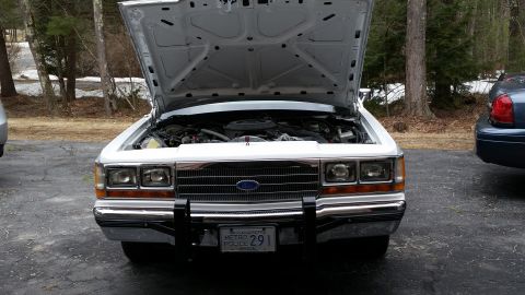 1991 Ford LTD Crown Victoria - Front view of a 1991 Ford Crown Victoria LTD police car with its hood open, parked next to another vehicle.