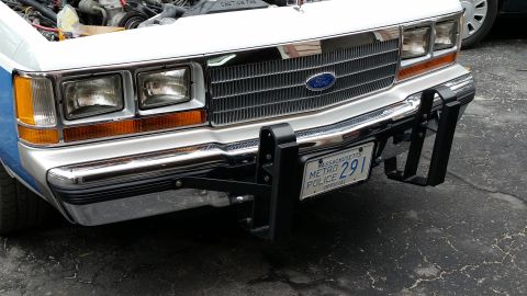 1991 Ford LTD Crown Victoria - Front view of a white and blue police car, showing its grille, headlights, and a Massachusetts license plate.