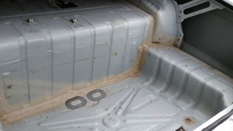 1991 Ford LTD Crown Victoria - The bare metal interior of a car's trunk shows the floor and side panels, with sealant applied.