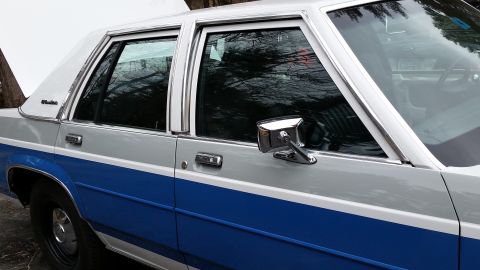 1991 Ford LTD Crown Victoria - Side view of a two-tone silver and blue 1991 Ford Crown Victoria sedan with its hood open.