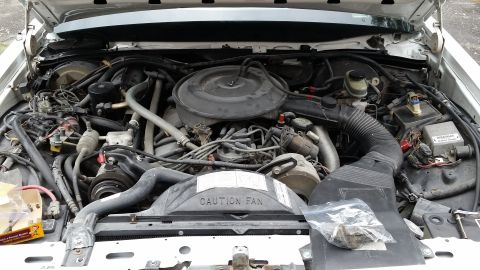 1991 Ford LTD Crown Victoria - The engine bay of a 1991 Ford Crown Victoria LTD, showing the engine and "CAUTION FAN" label on the radiator shroud.