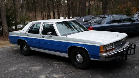 1991 Ford LTD Crown Victoria - A two-tone Ford Crown Victoria, likely a 1991 model, is parked outdoors with other vehicles in the background.