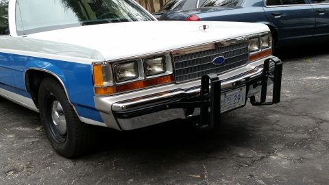 1991 Ford LTD Crown Victoria - This police car, identified as a 1991 Ford Crown Victoria LTD, is parked outdoors with a push bar attached to its front bumper.