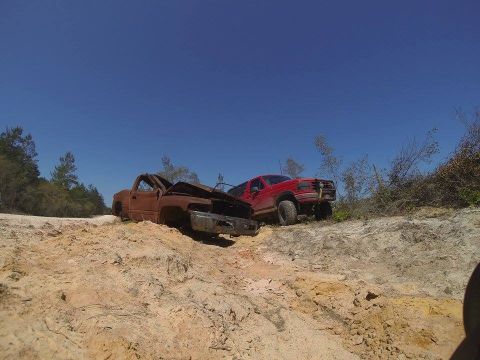 1995 Ford Bronco - Two trucks are stuck in the sand on an off-road trail under a clear blue sky.