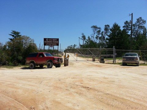 1995 Ford Bronco - A red SUV is parked near the entrance to the U.S. Navy Bombing Range, with another vehicle visible further down the road.